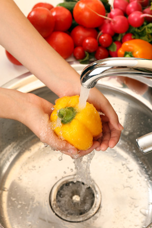 Woman's hands washing pepper in sinkの写真素材