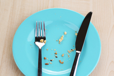 Plate with crumbs on wooden background