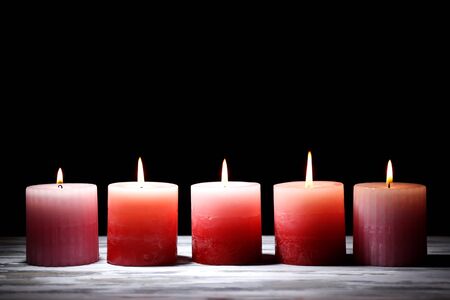 Beautiful candles with flowers on wooden table, on dark の写真素材
