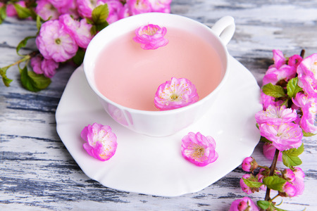 Beautiful fruit blossom with cup of tea on table close-upの写真素材
