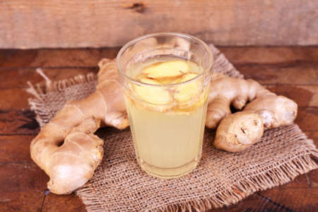 Ginger drink and ginger root on sackcloth napkin on wooden table