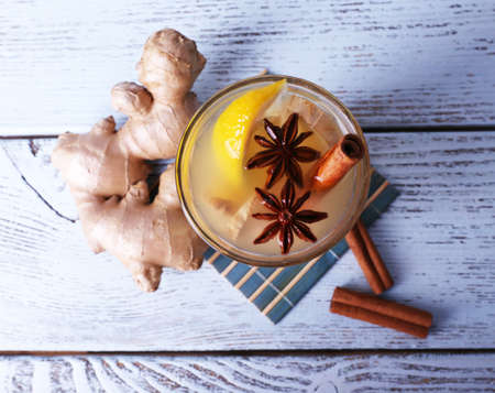 Glass of ginger drink with lemon on bamboo napkin on wooden backgroundの写真素材