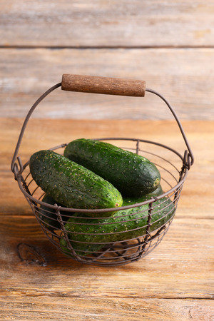 Cucumbers in wicker basket on wooden backgroundの写真素材