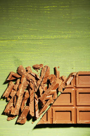 Milk chocolate bar on color wooden background