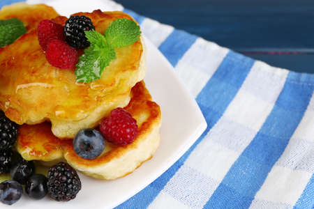 Tasty pancake with fresh berries and mint leaf on plate, on color wooden 