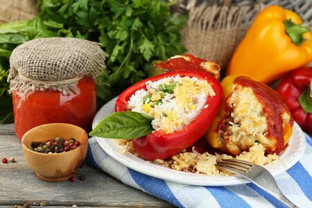 Composition with prepared stuffed peppers on plate and fresh herbs, spices and vegetables, on wooden backgroundの写真素材
