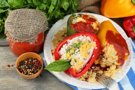 Composition with prepared stuffed peppers on plate and fresh herbs, spices and vegetables, on wooden backgroundの写真素材