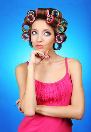 Beautiful girl in hair curlers on blue backgroundの写真素材