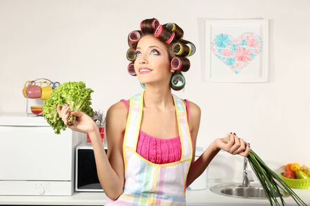 Beautiful girl in hair curlers in kitchenの写真素材