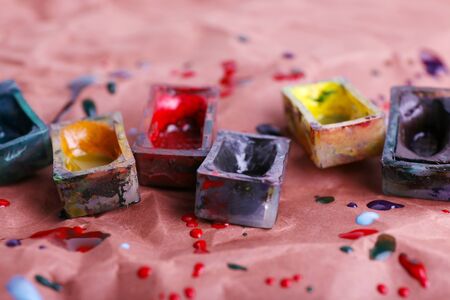 Watercolor paint cubes and spilled paint on brown paper backgroundの写真素材