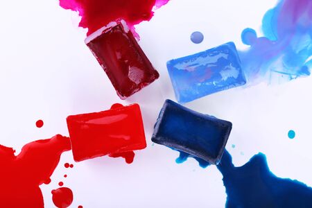 Watercolor paint cubes and spilled paint isolated on whiteの写真素材