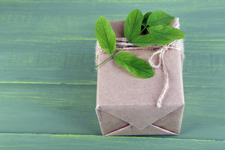 Natural style handcrafted gift box with fresh leaves and rustic twine, on wooden backgroundの写真素材