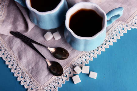 Cups of coffee with sugar and napkin on wooden tableの写真素材
