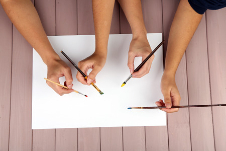 Two girls painting with paintbrush and colorful paintsの写真素材