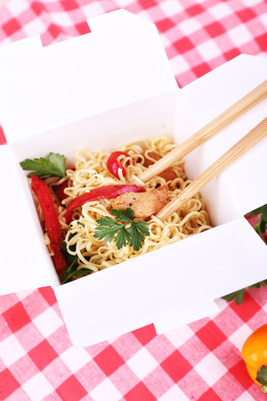 Chinese noodles and sticks in takeaway box on fabric backgroundの写真素材