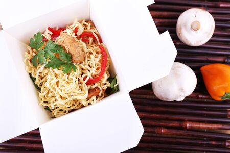 Chinese noodles in takeaway box on bamboo mat backgroundの写真素材