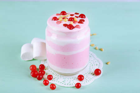 Cranberry milk dessert in glass jar, on color wooden backgroundの写真素材