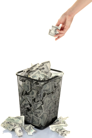 Hand throwing money into trash can isolated on whiteの写真素材