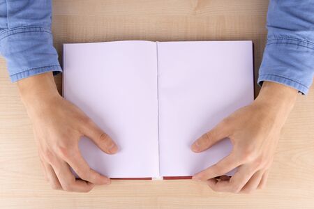 Men reading empty open book on wooden table backgroundの写真素材