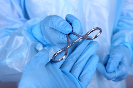 Surgeon's hands holding medical instrument closeupの写真素材