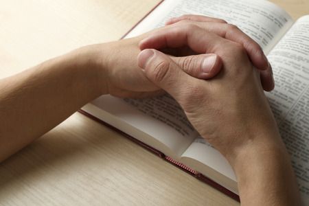 Male hands with Bible on wooden table