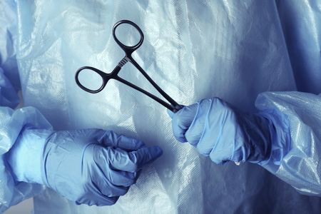 Surgeon's hands holding medical instrument closeupの写真素材