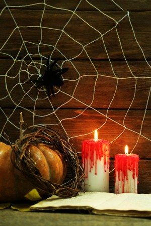 Halloween decoration with spider on web, book, pumpkin and candles on wooden backgroundの写真素材