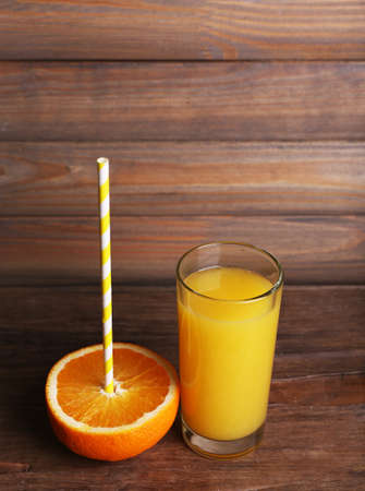 Glass of orange juice and fresh orange on wooden table on wooden wall backgroundの写真素材