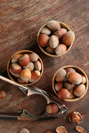 Hazelnuts in wooden bowls, on napkin on wooden backgroundの写真素材