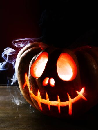 Halloween pumpkin on table on dark red backgroundの写真素材