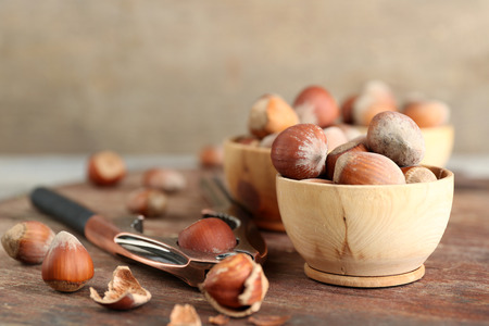 Hazelnuts in wooden bowls, on napkin on wooden background