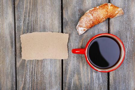 Composition of coffee, fresh croissant and paper card on wooden backgroundの写真素材