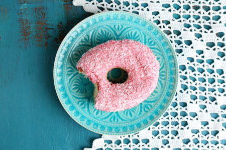 Bitten delicious donut on plate on wooden table close-upの写真素材