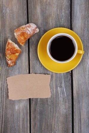 Composition of coffee, fresh croissant and paper card on wooden backgroundの写真素材