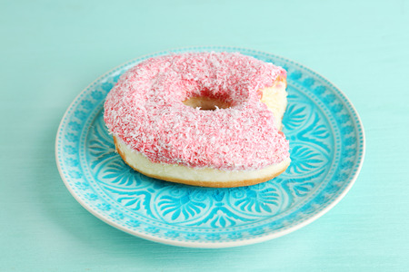Bitten delicious donut on plate on wooden table close-upの写真素材
