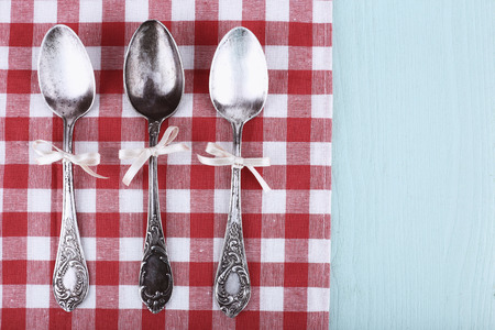 Metal spoons on checkered napkin on light blue backgroundの写真素材