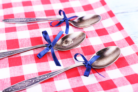 Metal spoons on checkered napkin on light blue backgroundの写真素材