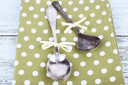 Metal spoons on green polka dot napkin on wooden backgroundの写真素材