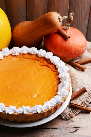 Composition of homemade pumpkin pie on plate and fresh pumpkins on wooden backgroundの写真素材