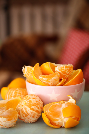 Sweet tangerines and oranges on table in bowl in roomの写真素材