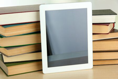 Tablet and books on light background