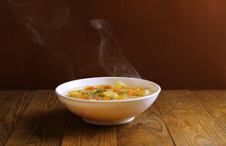 Delicious home cooked food with steam on table on brown backgroundの写真素材
