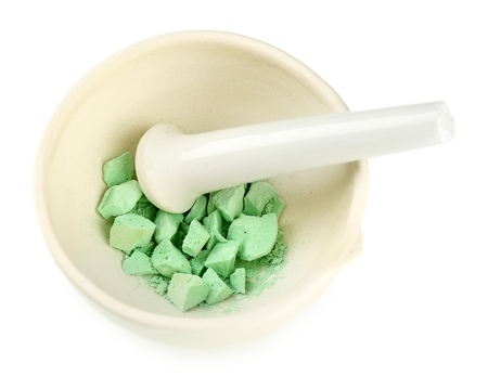 Laboratory pestle in mortar with ground material, isolated on whiteの写真素材
