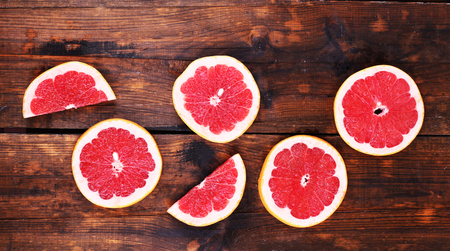 Ripe slices grapefruit on wooden backgroundの写真素材