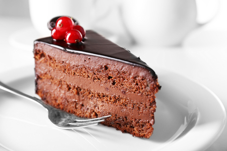 Delicious chocolate cake on plate on table on light backgroundの写真素材