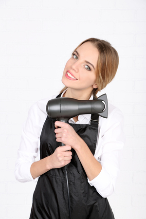 Beautiful girl hairdresser on light backgroundの写真素材