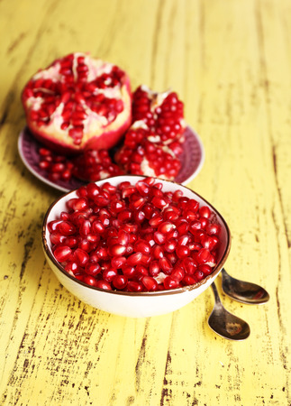 Beautiful composition with juicy  pomegranate seeds, on yellow wooden tableの写真素材