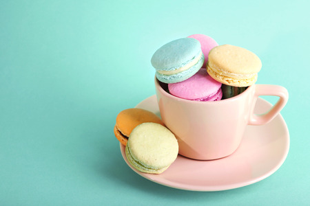 Assortment of gentle colorful macaroons in colorful mug on color backgroundの写真素材
