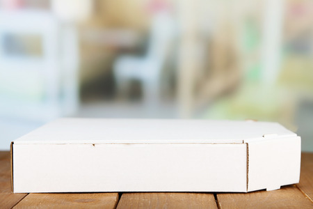 Empty cardboard pizza box on wooden table, on light background