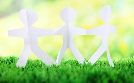 Paper group of people holding hands on green grass on light backgroundの写真素材